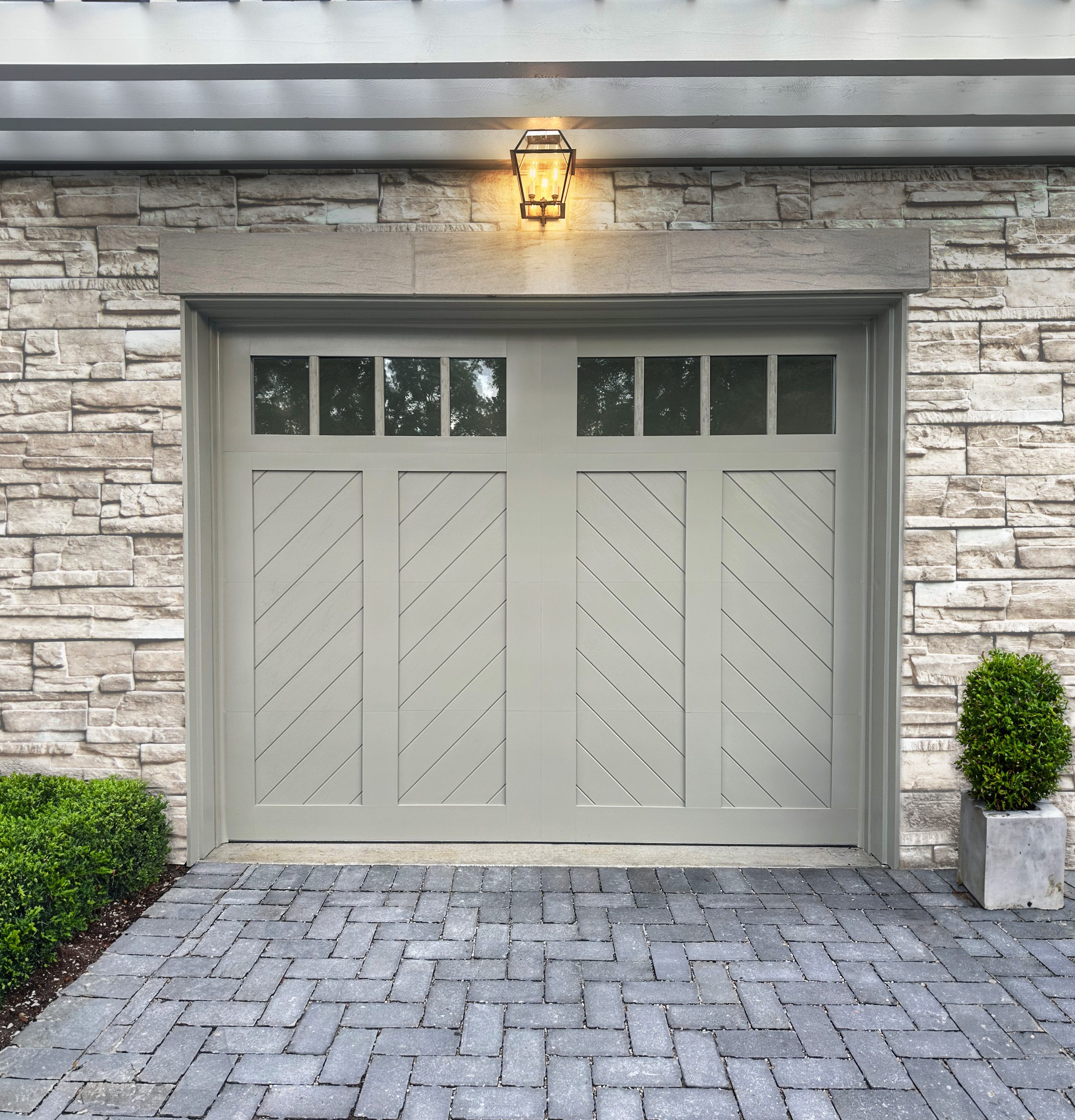 Clopay Canyon Ridge faux wood carriage house garage door with chevron design on a stone home
